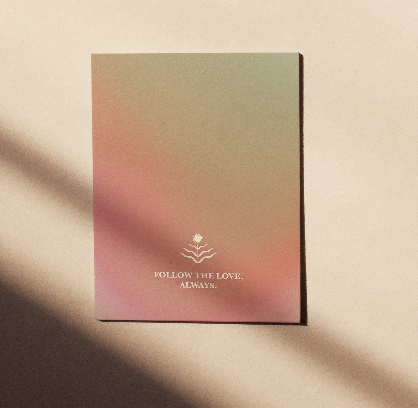 Postkarte "Follow the Love" im DIN-A6-Format von Anna Cosma mit weichen, chakra-inspirierten Farbverläufen in Rosa- und Grüntönen, einem kleinen Sonnen-Symbol und dem Text „FOLLOW THE LOVE, ALWAYS.“.