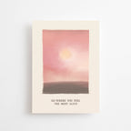 Postkarte „Go where you feel the Most Alive“ im DIN-A6-Format mit einer stimmungsvollen Illustration in Rosé-Tönen, einer sanften Sonne und dem Schriftzug vor hellem Hintergrund.