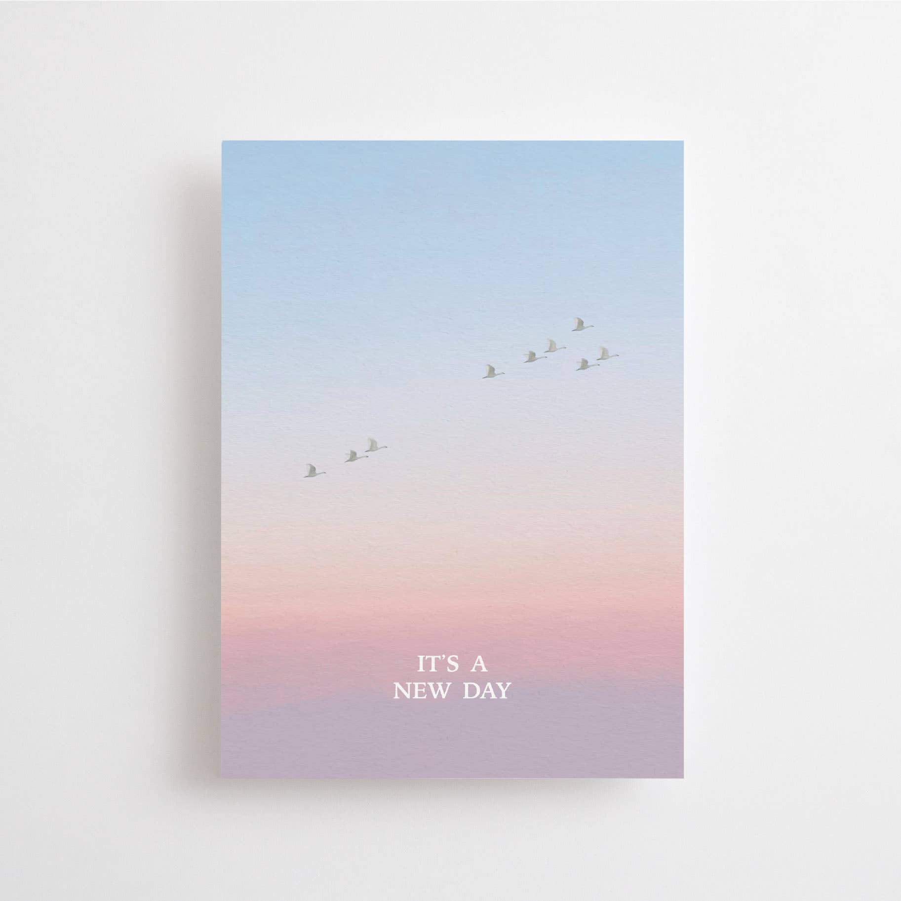 Postkarte „It's a New Day“ im DIN-A6-Format mit einem stimmungsvollen Farbverlauf, fliegenden Vögeln und dem Schriftzug vor einer natürlichen Landschaft.
