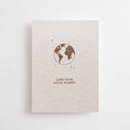 Postkarte "Love your Local Planet" im DIN-A6-Format von Anna Cosma aus strukturiertem Graspapier mit einer braunen Illustration der Erde und kleinen Sternen.