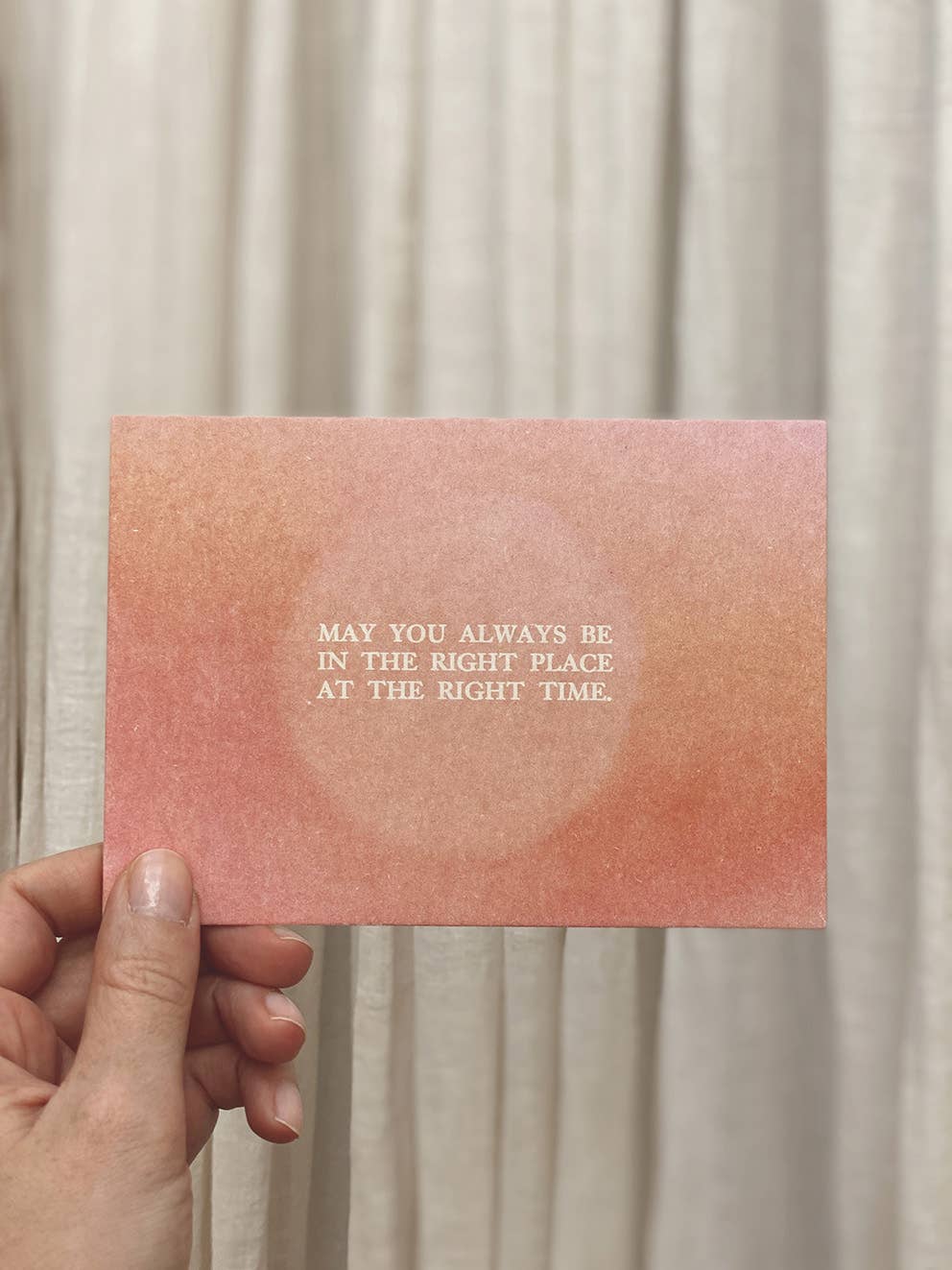 Postkarte „Right Place Right Time“ im DIN-A6-Format mit einem warmen rosafarbenen Farbverlauf, einem zentralen Lichtkreis und dem englischen Schriftzug vor hellem Hintergrund.