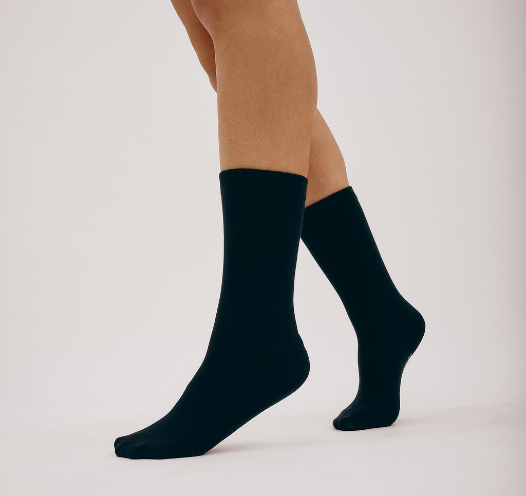 Schwarze Core Crew Socks in klassischer Crew-Länge an den Beinen eines Modells vor hellem Hintergrund.