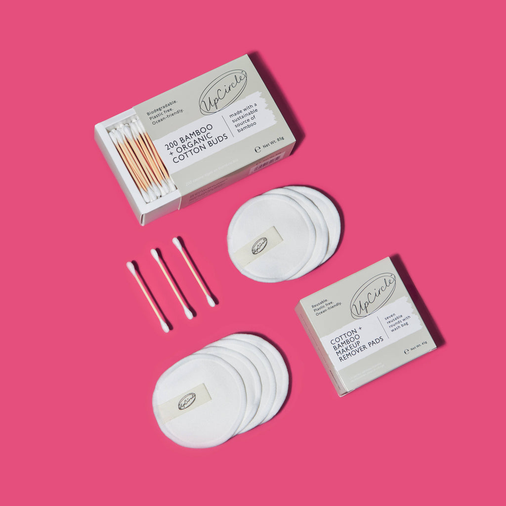 Sieben weiße, runde Make-up-Pads auf einem hellen Fliesenboden neben einem geöffneten Netzbeutel.