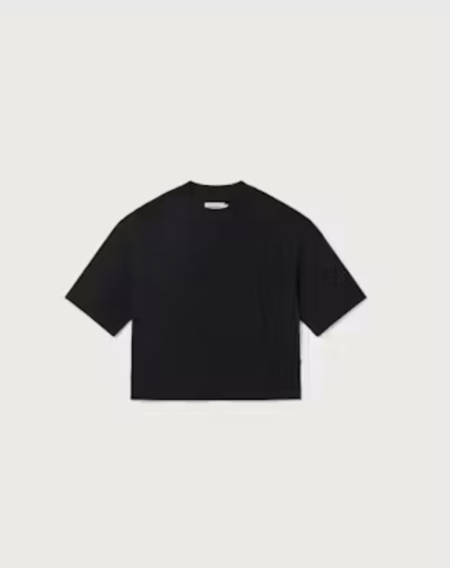 Weibliches Model mit rötlichen Haaren trägt ein schwarzes Black Lena Tee von Thinking Mu mit Rundhalsausschnitt zu blauen Jeans.