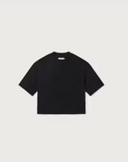 Weibliches Model mit rötlichen Haaren trägt ein schwarzes Black Lena Tee von Thinking Mu mit Rundhalsausschnitt zu blauen Jeans.