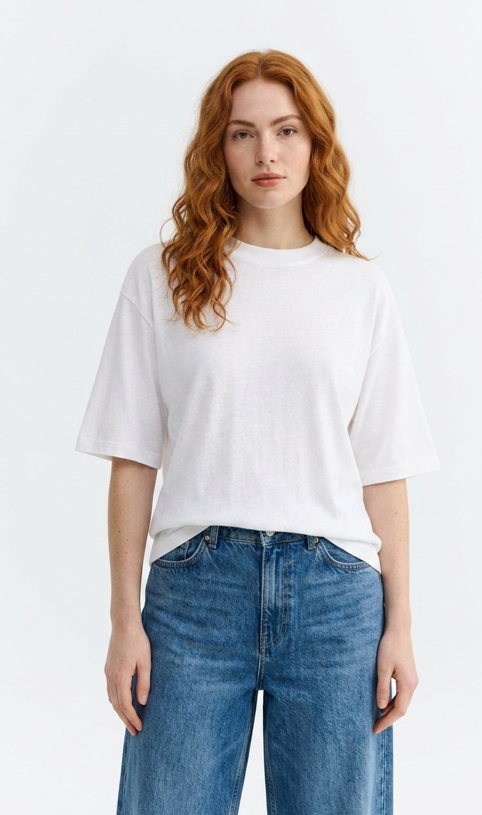 Weibliches Model mit rötlichen Haaren trägt ein weißes White Lena Tee von Thinking Mu mit Rundhalsausschnitt zu blauen Jeans.