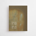"You are the light" im DIN-A6-Format von Anna Cosma mit einem warmen, erdtonfarbenen Hintergrund und dem weißen Text „You are the light. You are the sun“.