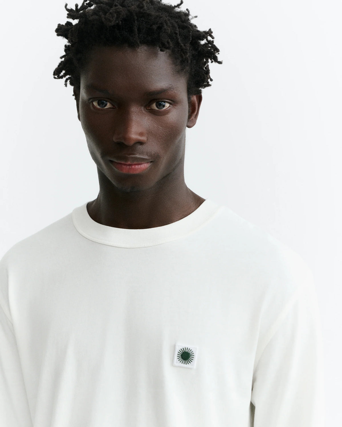 weißes Langarmshirt Big Sol White Emilio Tee von Thinking Mu mit Rundhalsausschnitt und grünem „Big Sol“-Sonnenprint auf der Rückseite.