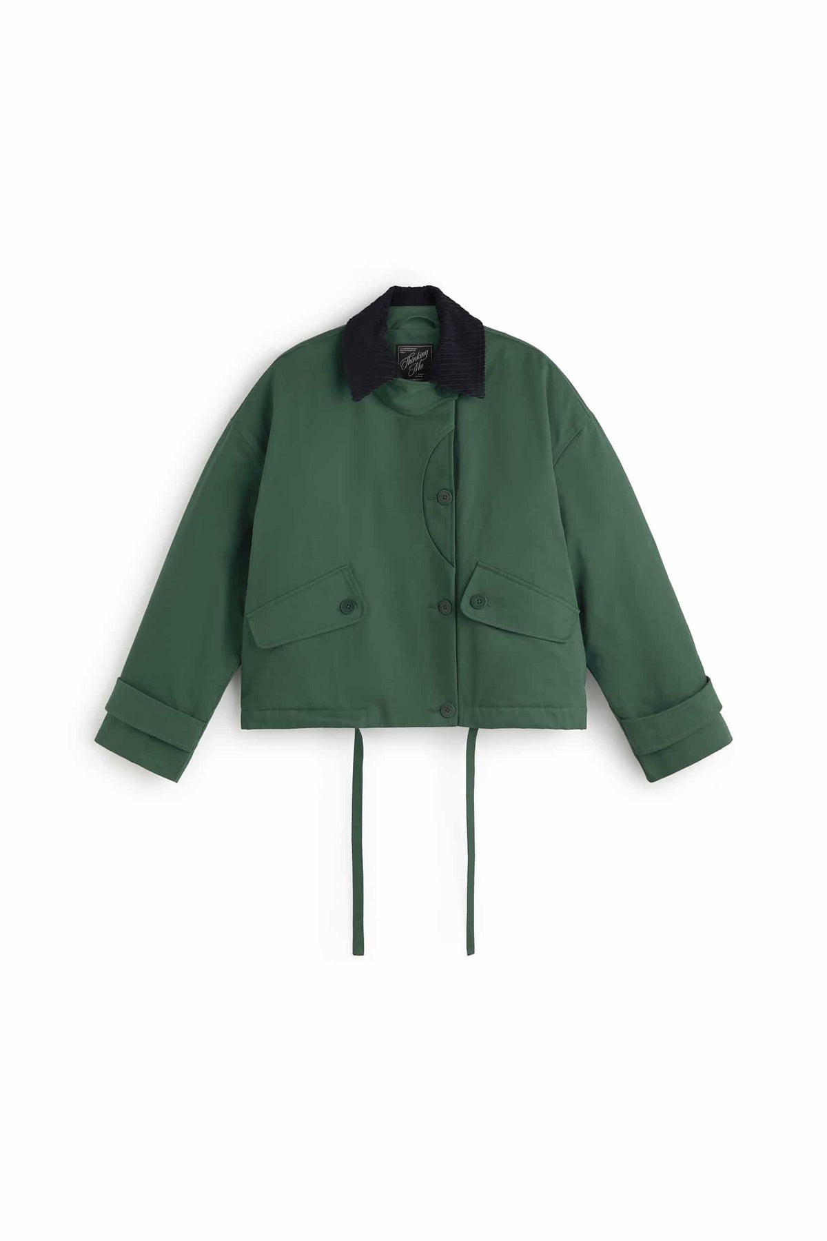 Grüne Jacke "Norma" von Thinking Mu mit dunklem Cord-Kragen, Knöpfen und herabhängenden Bändern am Saum vor hellem Hintergrund.