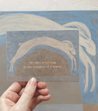 "No Road is too long" im DIN-A6-Format von Anna Cosma mit einem springenden weißen Hasen über eine Hügellandschaft vor blauschattiertem Hintergrund und dem Text „No road is too long in the company of a friend.“.