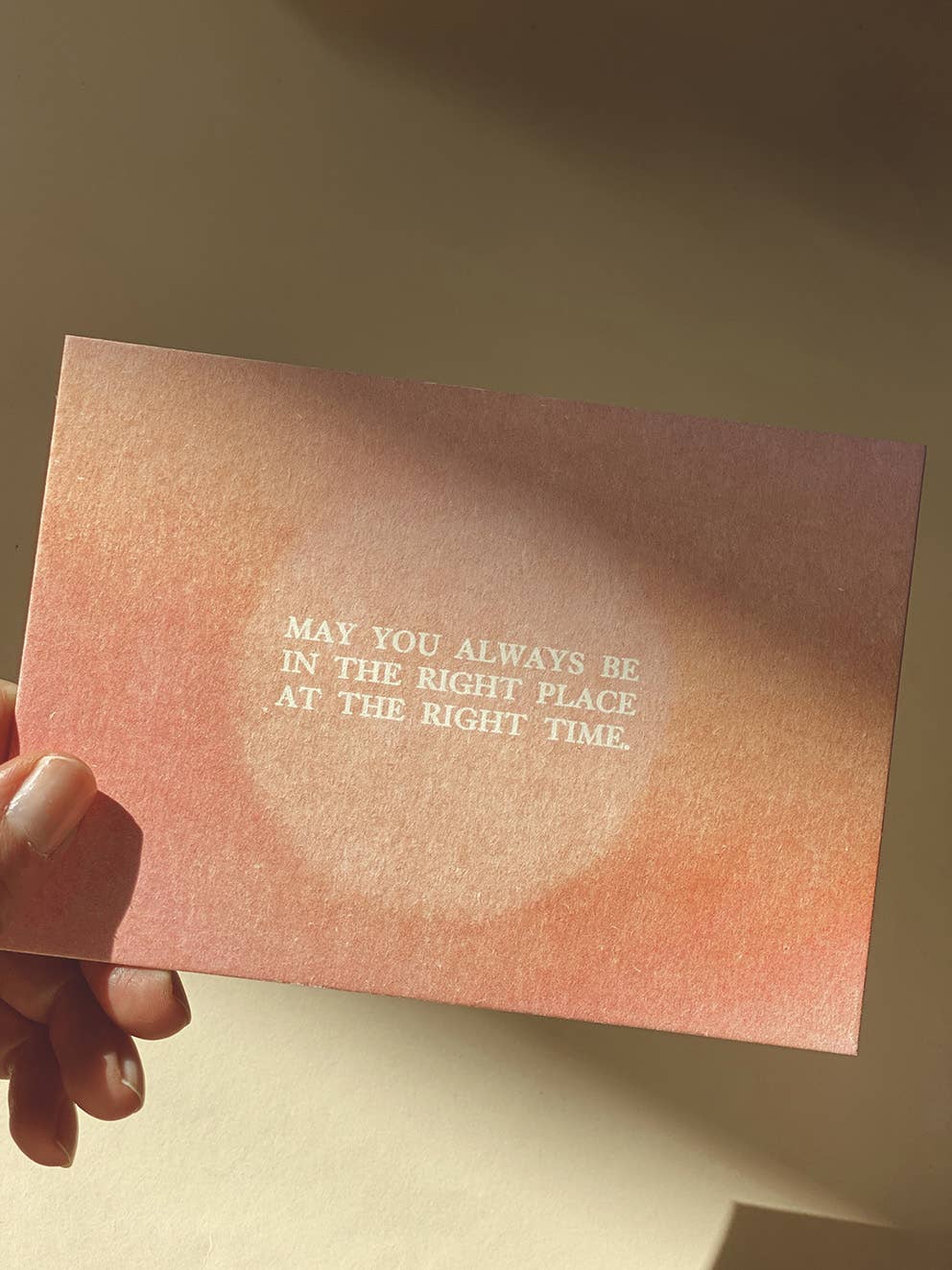 Postkarte „Right Place Right Time“ im DIN-A6-Format mit einem warmen rosafarbenen Farbverlauf, einem zentralen Lichtkreis und dem englischen Schriftzug vor hellem Hintergrund.
