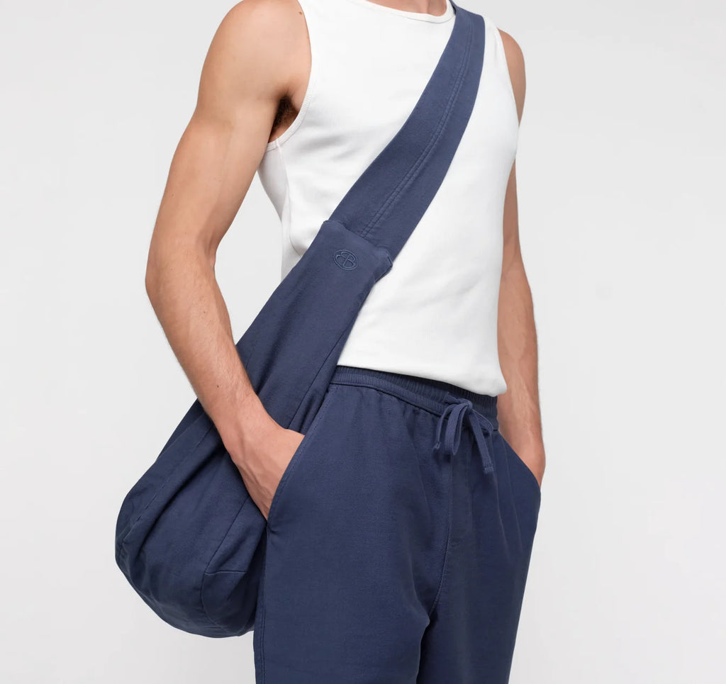 Männliches Model trägt die dunkelblaue Alley Copenhagen Shoulder Bag lässig über der Schulter vor hellem Hintergrund.