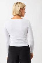 Blonde Frau von vorne in einem weißen Langarmshirt "Side Ruffled" mit Rundhalsausschnitt und seitlichen Raffungen vor hellem Hintergrund.