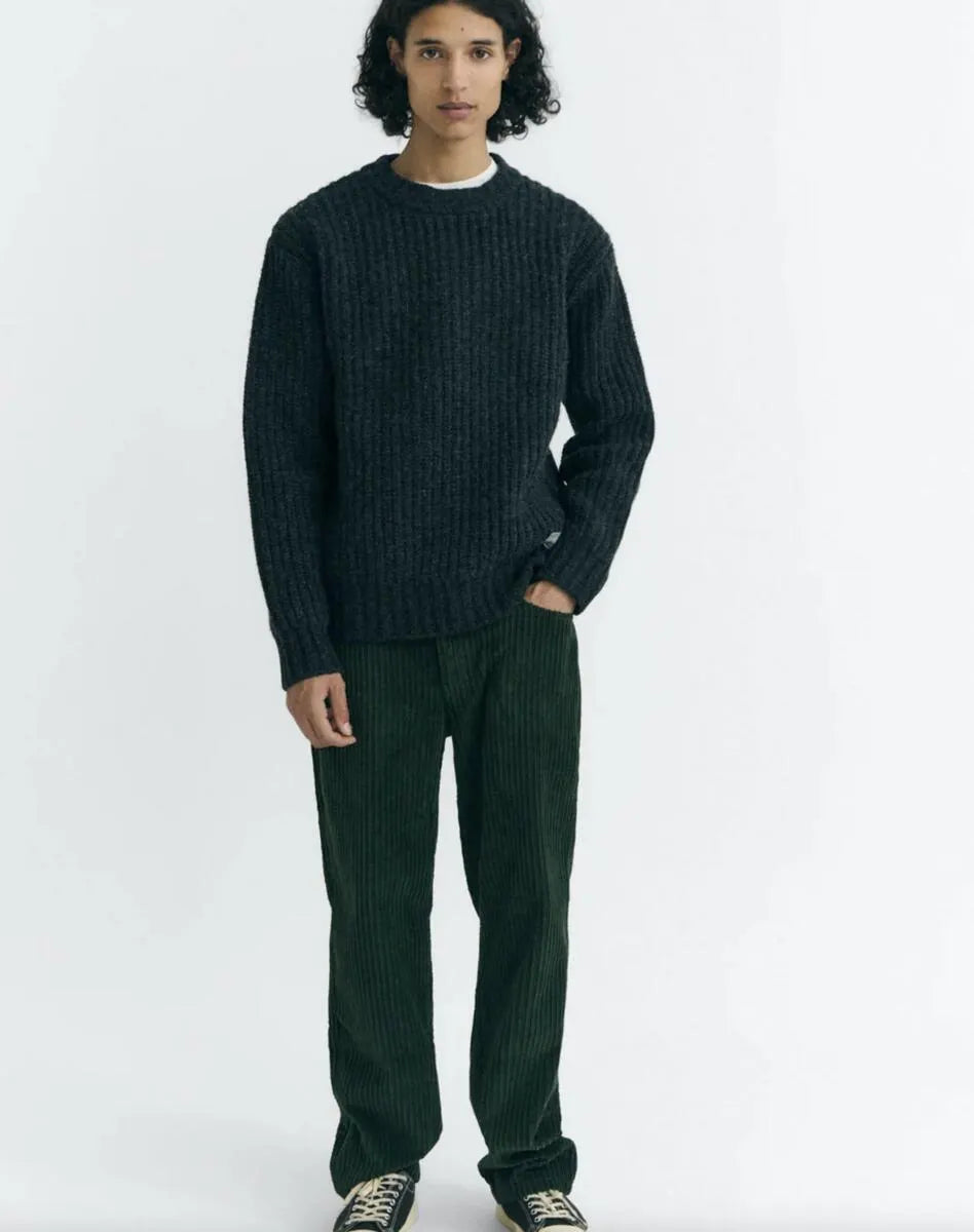 Dunkelgrüne Cordhose "David" von Thinking Mu aus feinem Cord-Stoff mit klassischen Taschen und Gürtelschlaufen vor hellem Hintergrund.