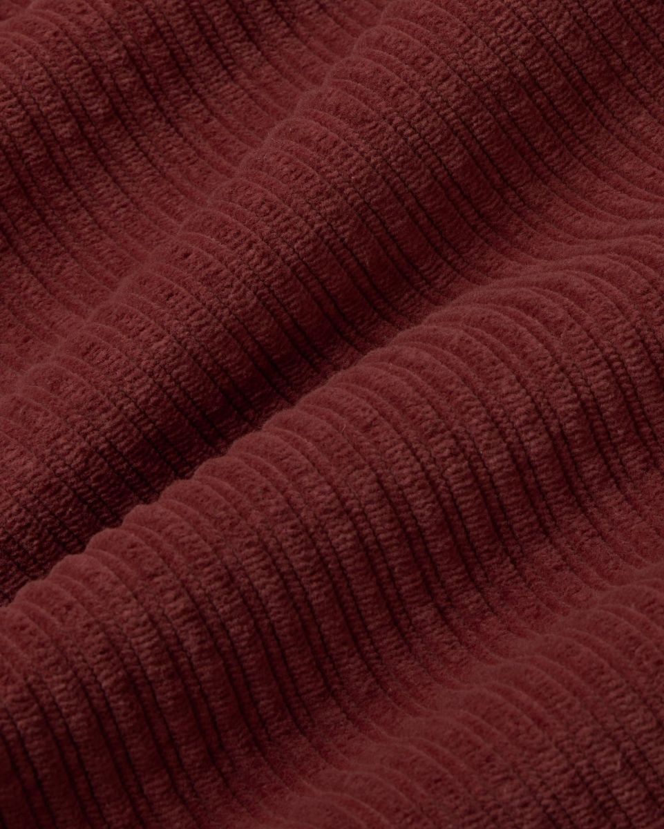 Mahagonifarbene Cordhose "Hedda" aus 100% Bio-Baumwolle mit geradem Bein und aufgesetzten Taschen vor hellem Hintergrund.