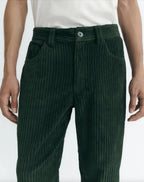 Dunkelgrüne Cordhose "David" von Thinking Mu aus feinem Cord-Stoff mit klassischen Taschen und Gürtelschlaufen vor hellem Hintergrund.