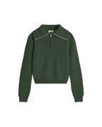 Dunkelgrüner Pullover "Tanit" von Thinking Mu aus Merinowolle mit hohem Kragen, silbernem Reißverschluss und Label am Ausschnitt vor hellem Hintergrund.