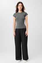 Person von vorne in einem dunkelgrauen, gerippten Slim-Fit-T-Shirt mit kurzen Ärmeln und Raglanschnitt vor hellem Hintergrund.