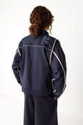 Rückansicht der HALTSU Wendejacke mit hellen Kontrastpaspeln und eingearbeitetem Logo.