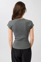 Person von vorne in einem dunkelgrauen, gerippten Slim-Fit-T-Shirt mit kurzen Ärmeln und Raglanschnitt vor hellem Hintergrund.