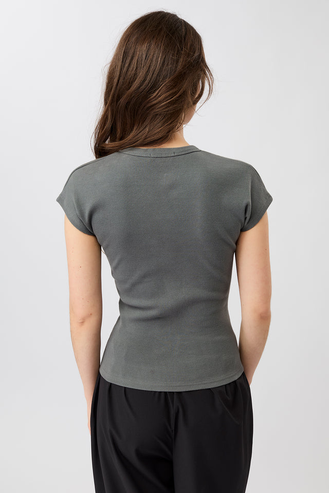 Person von vorne in einem dunkelgrauen, gerippten Slim-Fit-T-Shirt mit kurzen Ärmeln und Raglanschnitt vor hellem Hintergrund.