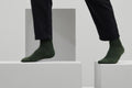 Ein Paar gestrickte Socken aus Wolle in meliertem Waldgrün vor weißem Hintergrund.