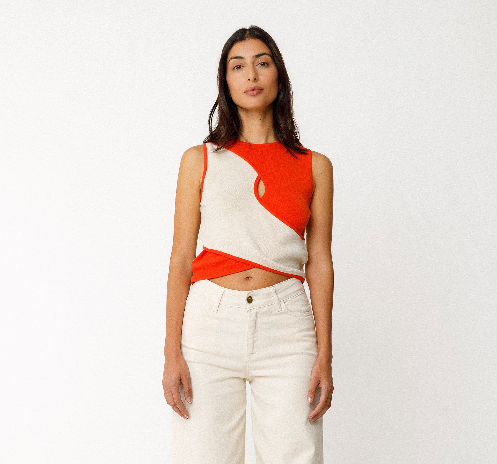 rontansicht des orangefarbenen NERE-GOTS Strick-Tops an einem Modell, kombiniert mit einer hellen Hose.