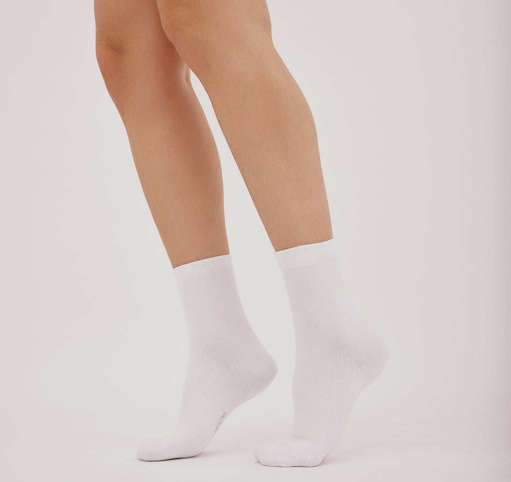 weiße Core Crew Socks in klassischer Crew-Länge an den Beinen eines Modells vor hellem Hintergrund.