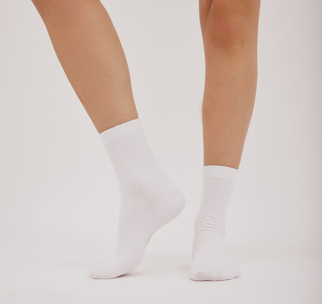 weiße Core Crew Socks in klassischer Crew-Länge an den Beinen eines Modells vor hellem Hintergrund.