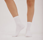 weiße Core Crew Socks in klassischer Crew-Länge an den Beinen eines Modells vor hellem Hintergrund.