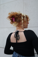 Rückansicht einer Frau mit lockigem, rötlich-blondem Haar, das lässig von der rosa Hope Haarklammer gehalten wird.