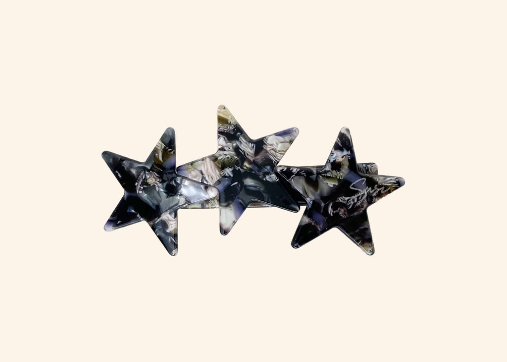 Nahaufnahme des Starlight Haarclips aus dunklem, gemustertem Cellulose-Acetat in Form von drei aneinandergereihten Sternen.